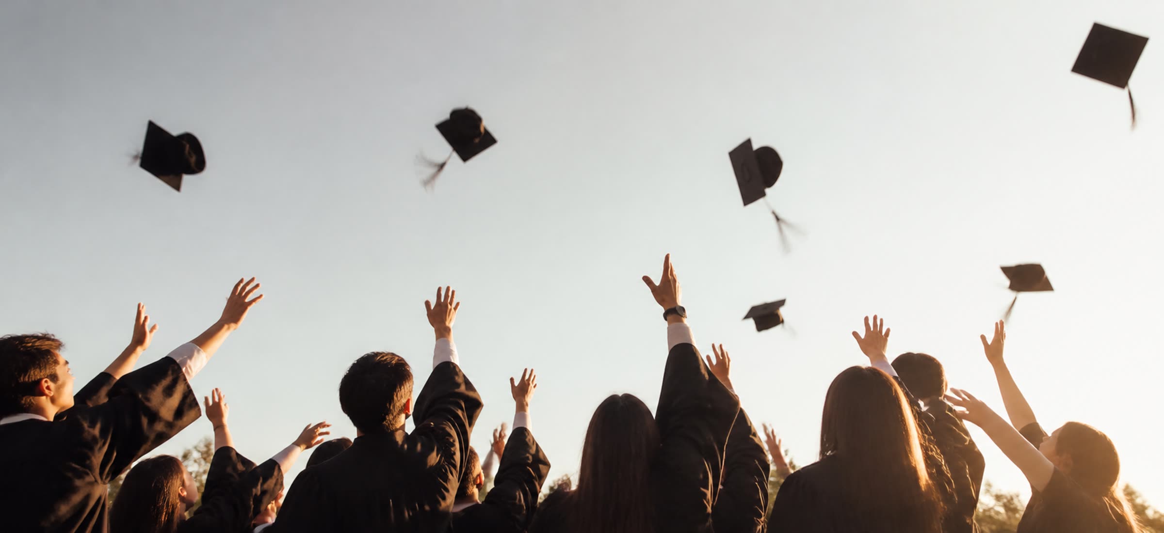 毕业典礼上抛起学士帽的学生 · Graduates throwing caps at a ceremony